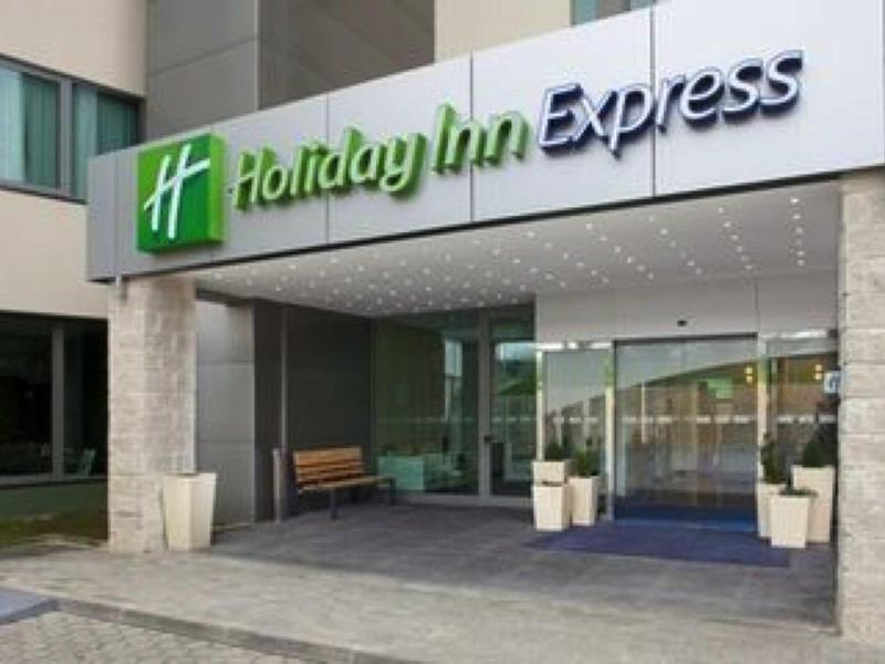 Area d'ingresso di un hotel Holiday Inn Express con porte in vetro e vasi di piante.