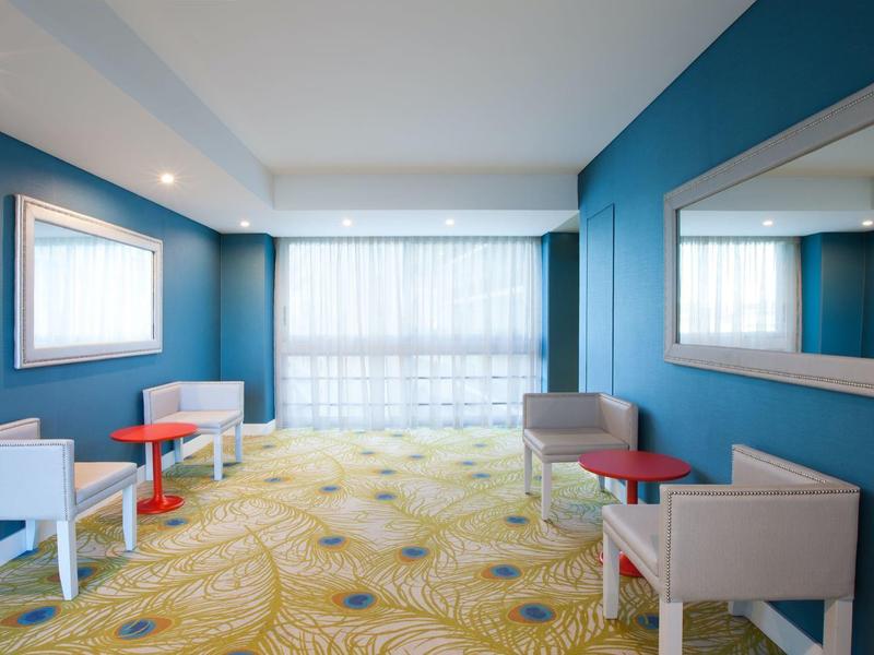 Area d'attesa luminosa con pareti blu, pavimento moquettato e più posti a sedere.