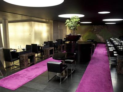 Modernes Hotelrestaurant mit schwarzen Möbeln und pinken Teppichläufern