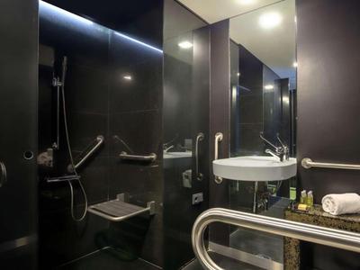 Modernes, barrierefreies Badezimmer mit dunkelgrauen Fliesen und Haltegriffen.