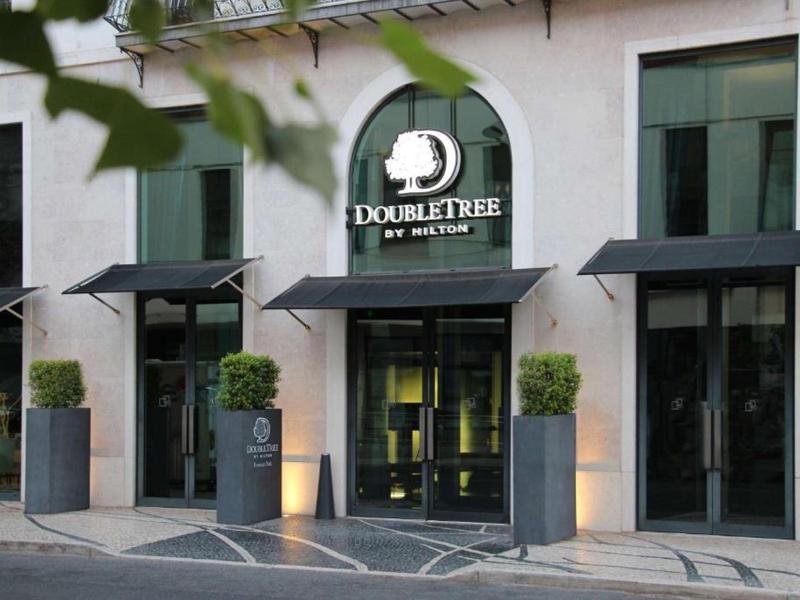 Ingresso di un hotel DoubleTree by Hilton con porte in vetro e piante sulla strada.