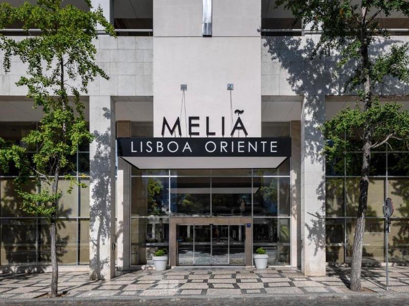 Ingresso dell'hotel Meliá Lisboa Oriente con facciata in vetro, alberi e ombre