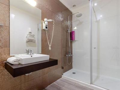 Moderní koupelna se sprchou, umyvadlem a fénem v teplých hnědých tónech.