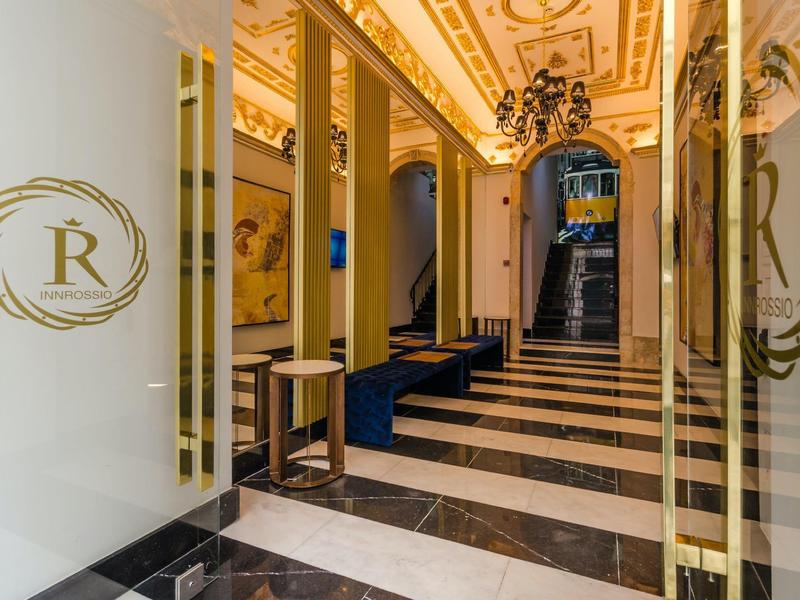 Elegante hall d'hotel con pavimento in marmo e decorazioni dorate dietro porte di vetro.