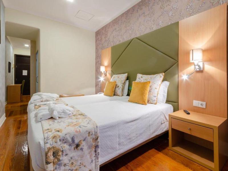 Camera d'hotel arredata modernamente con letto matrimoniale, comodino e illuminazione soffusa.