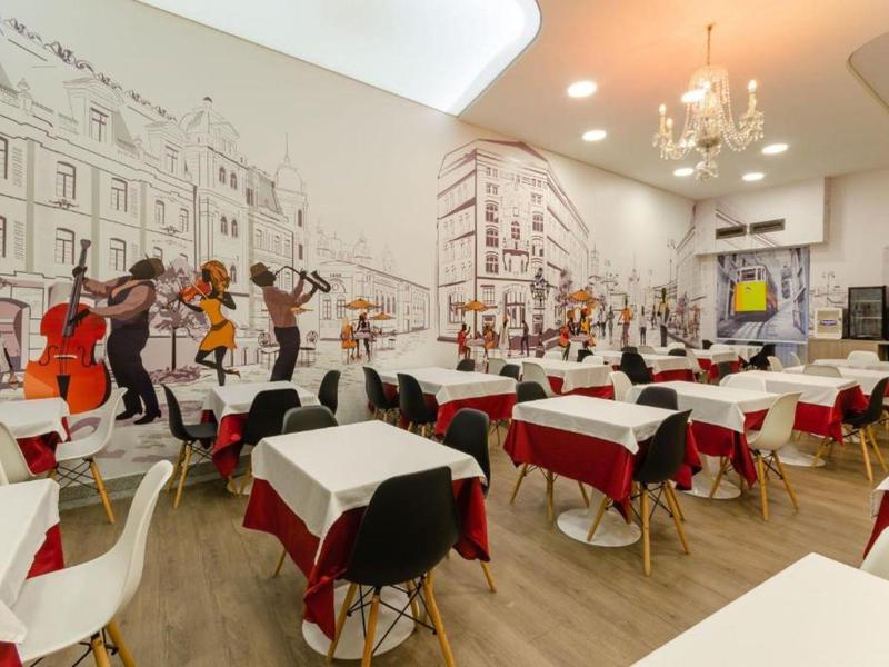 Ristorante moderno con tavoli bianchi e rossi e murales di musicisti.