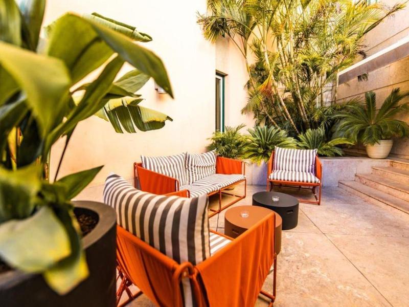 Accogliente area esterna con poltrone colorate e piante rigogliose su una terrazza dell'hotel.