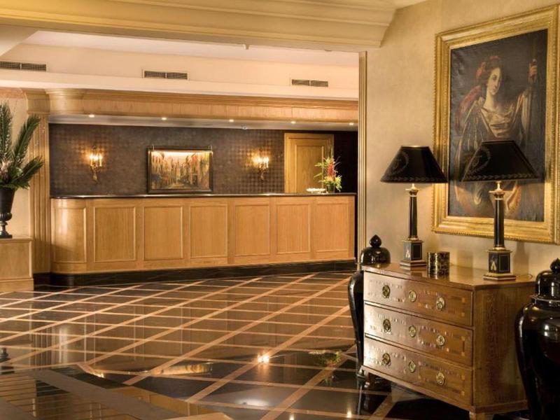 Ingresso di hotel elegante con pavimento in marmo, reception e arredi classici.
