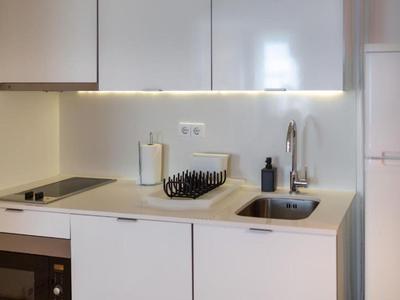 Angolo cottura moderno e minimalista con fornello, lavello e pensili in tonalità neutre.