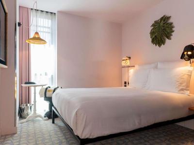 Camera d'hotel luminosa con letto grande, pareti bianche e decorazioni minime.