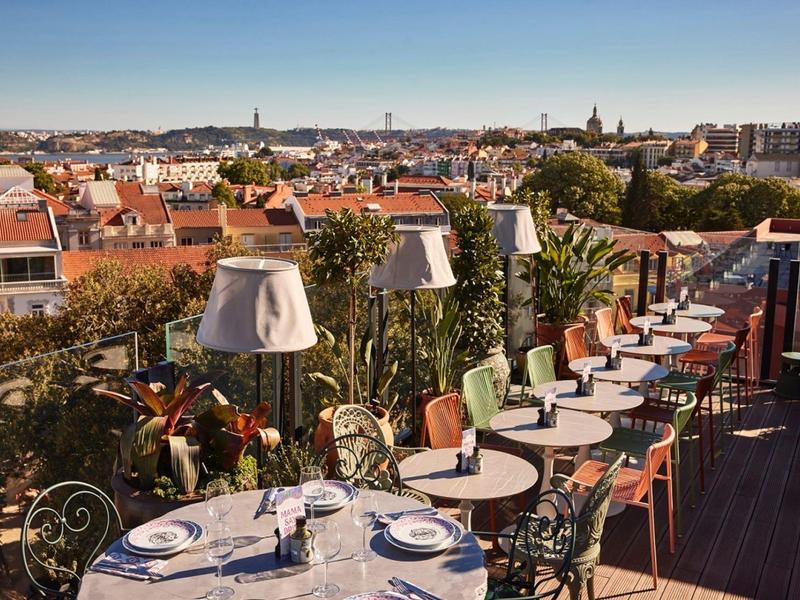 Terrazza panoramica con tavoli apparecchiati e vista sulla città sotto un cielo terso.