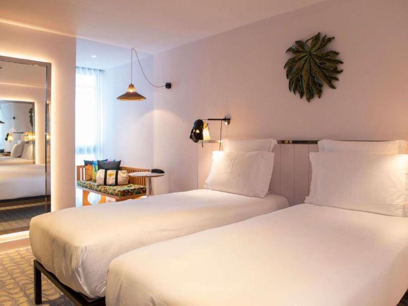 Camera d'hotel moderna con due letti singoli, decorazione da parete e illuminazione accogliente.