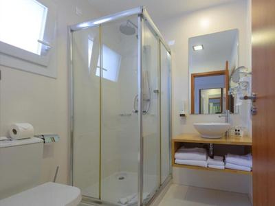 Bagno luminoso con doccia, lavabo, toilette e asciugamani sotto il lavabo.