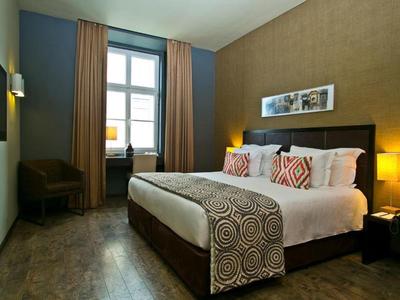 Camera d'hotel accogliente con letto grande, comodini e finestra con tende.