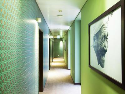 Pasillo con paredes pintadas de verde y un retrato en la pared derecha en un hotel.