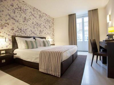 Camera d'hotel elegante con motivo floreale, letto matrimoniale e scrivania vicino alla finestra.