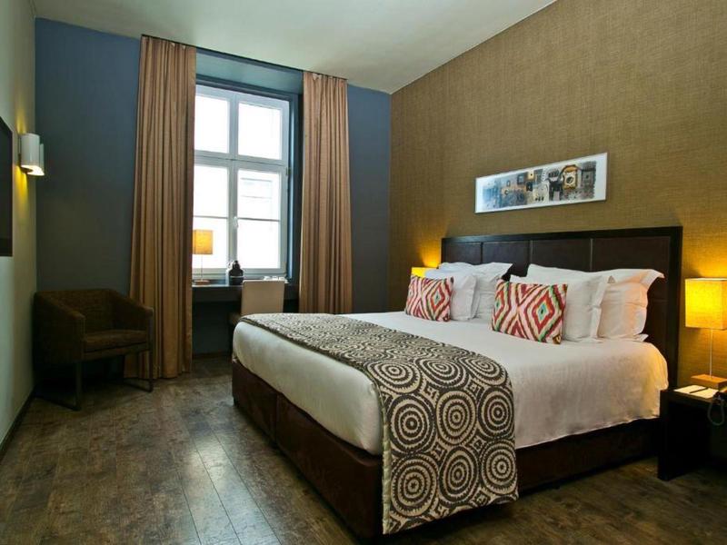 Camera d'hotel accogliente con letto grande, comodini e finestra con tende.