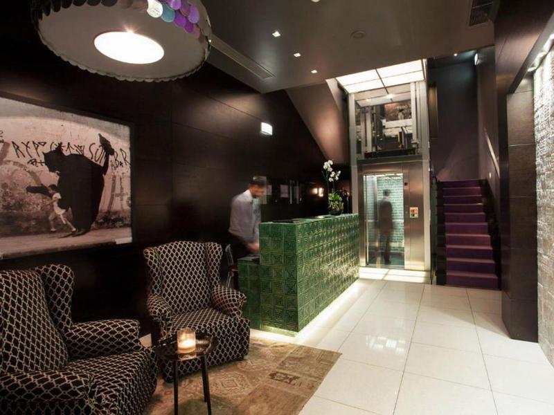 Hall dell'hotel moderno con comode poltrone, reception verde e ascensore in ambiente elegante.