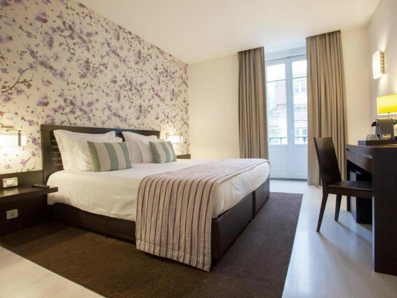 Camera d'hotel elegante con motivo floreale, letto matrimoniale e scrivania vicino alla finestra.