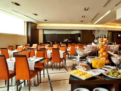 Hell beleuchteter Speiseraum mit gedeckten Tischen und Buffet im Vordergrund.