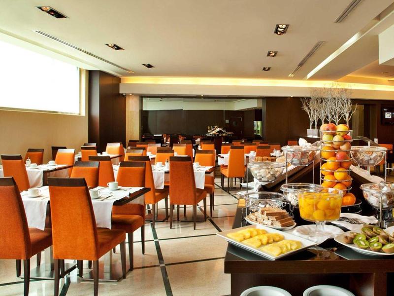 Ristorante elegante con sedie arancioni e buffet con frutta fresca e succhi.