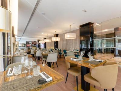 Modern hotel restaurant with wooden tables, comfortable chairs, and bright pendant lights.