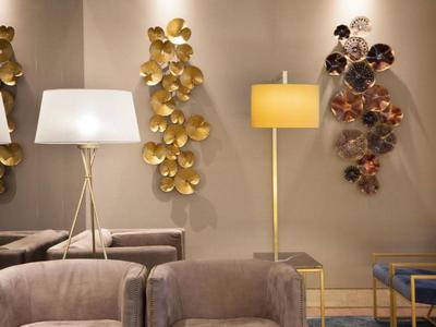 Modern seating area with two floor lamps and decorative wall pieces in warm tones.