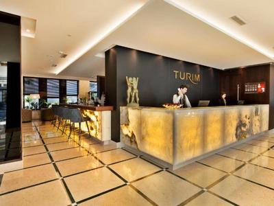 Modernes Hotel-Lobby mit großem, beleuchtetem Empfangstresen und eleganten Sitzbereichen im Hintergrund.