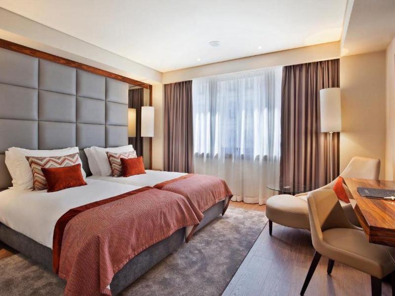 Camera d'hotel moderna con letto grande, scrivania e finestra con tende.