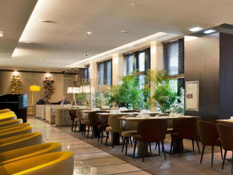 Ristorante d'hotel moderno con sedie gialle, grandi finestre e piante verdi