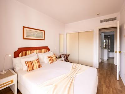 Camera d'hotel luminosa con letto matrimoniale, pavimento in legno e armadio a muro.