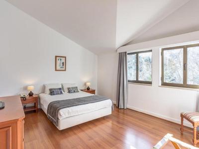 Camera d'albergo semplicemente arredata con letto matrimoniale, pavimento in legno e finestra grande.