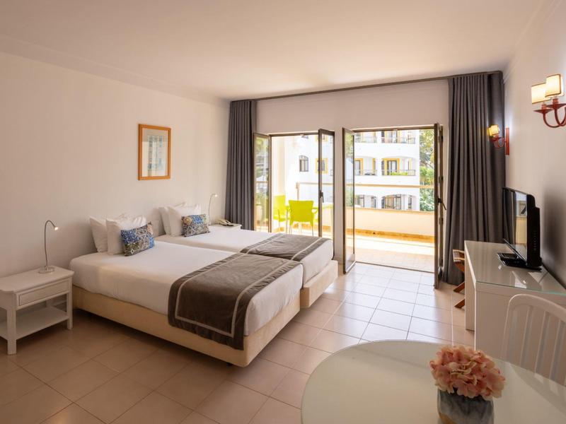 Světý hotelový pokoj s manželskou postelí, terasou a moderním dekorací