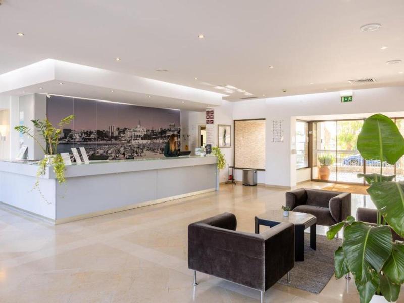 Světlá hotelová hala s moderní recepcí a posezením.