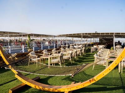 Outdoor seating with tables and chairs on green grass under clear sky at a resort.