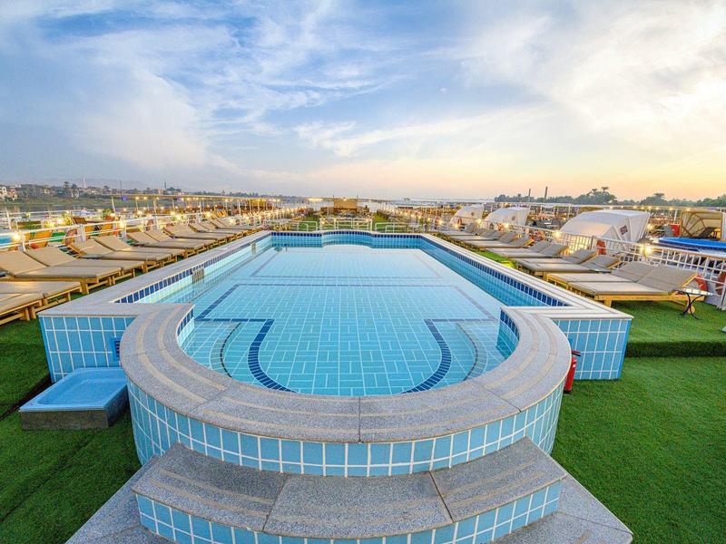 Piscina moderna en la azotea del hotel con vista a la ciudad y el cielo al atardecer.
