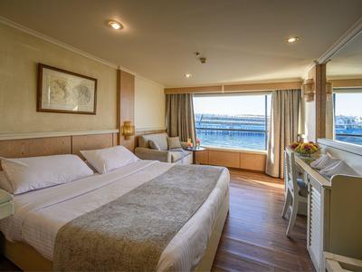 Camera d'hotel con letto matrimoniale, poltrona e finestra con vista sul mare.