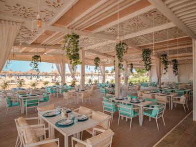 Espace restaurant ouvert et moderne avec plafonds en bois, moquette et vue sur la plage.
