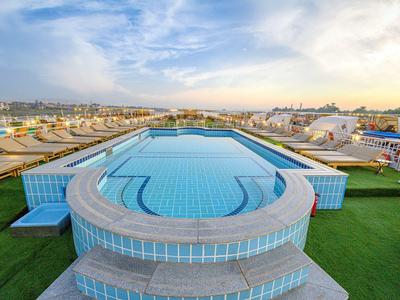 Piscina moderna en la azotea del hotel con vista a la ciudad y el cielo al atardecer.