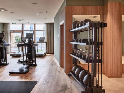 Moderne Fitnessräume mit Laufbändern, Gewichten und großen Fenstern mit Blick nach draußen.