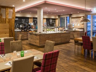 Modern eingerichteter Restaurantbereich mit Holzfußboden, Tischen und Buffet in warmem Licht.