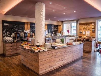 Ein heller Frühstücksraum mit einem hölzernen Buffetbereich und großer Auswahl an Speisen.