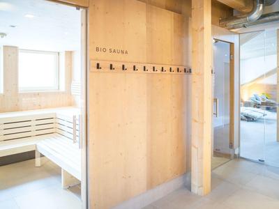 Heller Saunavorraum mit Holzbank, Wandhaken und Glaswand zum Treppenhaus.