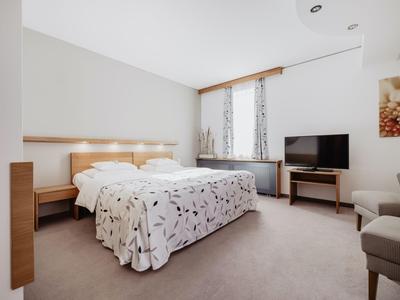 Modernes Hotelzimmer mit Doppelbett, Fernseher und Fenster mit Vorhängen