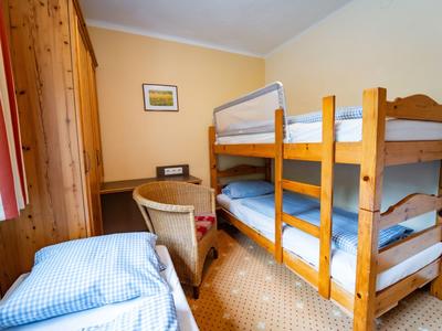 Kleines Zimmer mit Etagenbett, Einzelschlafplatz, Schreibtisch und Stuhl, gelbe Wände