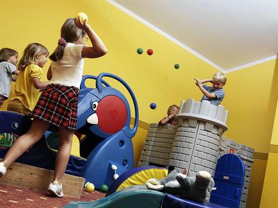 Kinder spielen fröhlich auf einem großen, bunten Klettergerüst in einem gelben Raum.