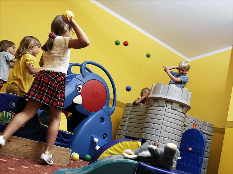 Kinder spielen fröhlich auf einem großen, bunten Klettergerüst in einem gelben Raum.