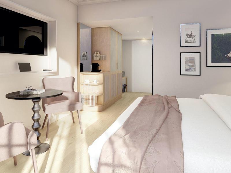 Modernes Hotelzimmer mit Bett, Wandbildern, Fernseher, Sitzbereich und heller Atmosphäre.