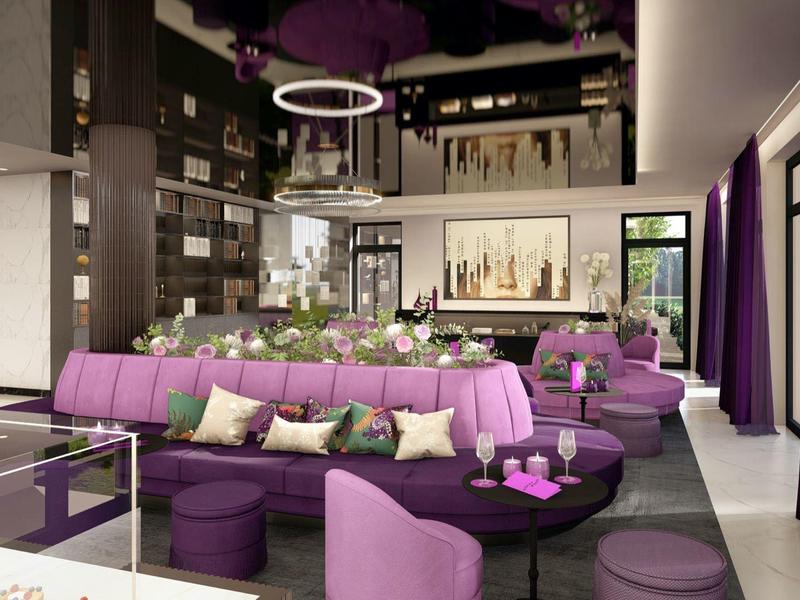 Moderne Lounge mit lila Sofas, Kissen, runden Tischen, Bücherregalen und großen Fenstern.