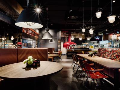 Modern eingerichtetes Restaurant mit Holztischen, Stühlen und warmen Lichtquellen.